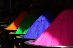 Orange, green, purple, and pink piles of pigment powders.