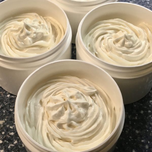 whipped body butter handmade in plastic jars with lids off.