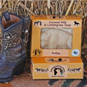 Coconut milk and lemongrass soap handmade buffalo design in soap box with plastic window surrounded by cowgirl boot, horse bit, and hay bale.